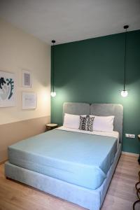 a bedroom with a large bed with a green wall at ΜΕΛΑΝΘΙΑ m2 in Preveza
