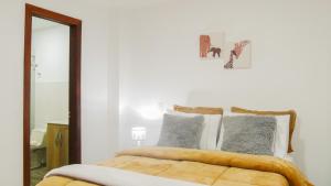 a white bedroom with a bed with a mirror at OCASSO JARDIN APARTAMENTO TURPIAL in Jardin
