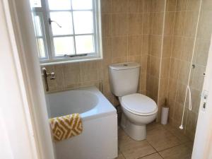 a bathroom with a toilet and a tub and a window at Spacious character cottage overlooking fields in Harrietsham