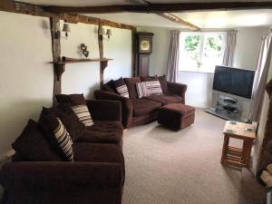 a living room with couches and a flat screen tv at Spacious character cottage overlooking fields in Harrietsham