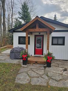 a tiny house with a red door and two plants at Bearfoot Bungalow in Sauble Beach