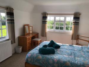 a bedroom with a bed with blue sheets and windows at Spacious character cottage overlooking fields in Harrietsham