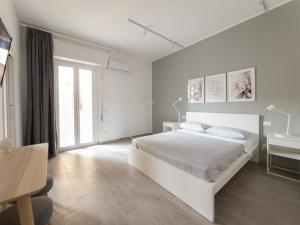 a white bedroom with a white bed and a desk at Serendipity room & relax in Palermo
