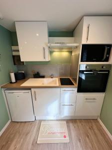 a kitchen with white cabinets and a sink and a microwave at L'Escale du Mont Saint Michel in Avranches +2 photos