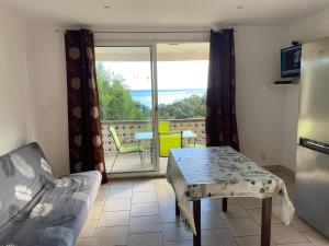 a living room with a table and a sliding glass door at Le Thyreneen in Sari Solenzara