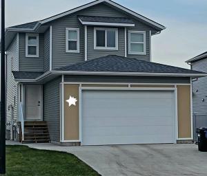 a gray house with a garage with a star on it at Olive Place in Saskatoon