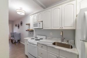 eine Küche mit weißen Schränken und einem Waschbecken in der Unterkunft Tiny Treasure in St Pete Beach