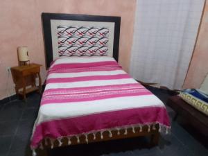 een slaapkamer met een bed met een paarse en witte deken bij Hospedaje Casa Cortés - Recamaras de Descanso en Tepoztlán Mor in Tepoztlán