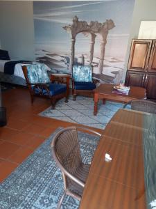 a living room with chairs and a table and a bed at Beit-El BnB in Polokwane
