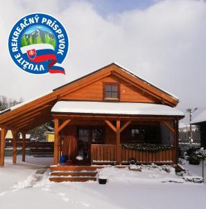 une cabane en rondins dans la neige avec le logo de l'université de pittsburgh dans l'établissement Chata Kaprík, à Liptovský Mikuláš