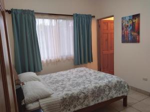 - une chambre avec un lit et une fenêtre avec des rideaux verts dans l'établissement Lourdes home, à San Isidro de El General