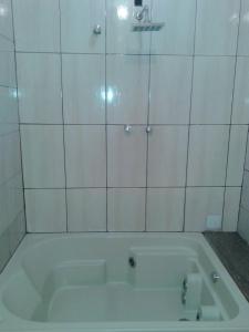 uma banheira na casa de banho com azulejos brancos em Sítio morada nova em Contagem