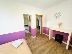 1 dormitorio con paredes de color púrpura y blanco y chimenea en ROSALES Apartamento y jardín en Oviedo