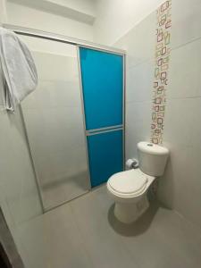a bathroom with a toilet and a shower with a blue door at La Reserva de UBA in El Socorro