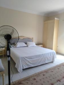 a bedroom with a white bed and a fan at الريف الاوروبي in Al Qaţā