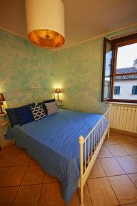 1 dormitorio con cama con sábanas azules y ventana en Dimora San Martino, en Offida