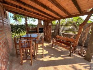 d'une terrasse avec une table, des chaises et un banc. dans l'établissement Pousada Tarumã challes 01, à Bonito