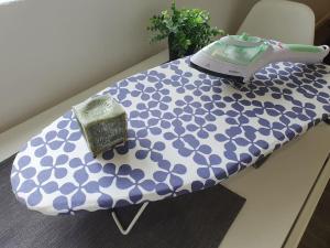 a table with a blue and white cover with a iron and a clock at Maisonnette climatisée avec piscine & Spa in Marseille