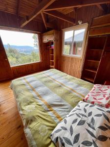 Cama grande en habitación con ventana en Cabañas Kalfvgen, en Valdivia