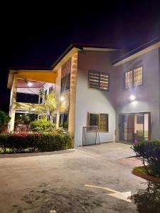 a large white building with a driveway at night at GHouse in Adentan