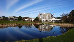 een groot gebouw naast een meer bij 't Klèène Genot in Hollum