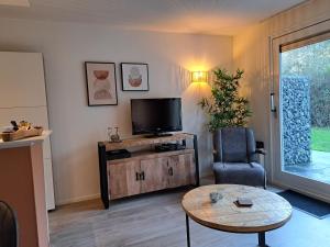 een woonkamer met een tv, een stoel en een tafel bij 't Klèène Genot in Hollum
