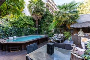 um quintal com uma banheira de hidromassagem e palmeiras em Maison avec piscine - Vincennes em Vincennes