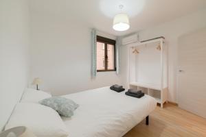 a bedroom with a white bed with two towels on it at TrendyHomes Granada - moderno apartamento a 15 minutos del centro in Granada