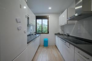 a kitchen with white cabinets and a blue trash can at TrendyHomes Granada - moderno apartamento a 15 minutos del centro in Granada