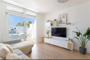 a living room with a flat screen tv on a white wall at Sea light in Puerto del Carmen