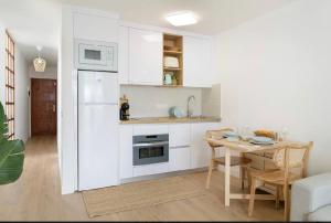 a kitchen with a table and a white refrigerator at Sea light in Puerto del Carmen