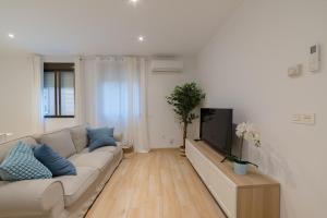a living room with a couch and a tv at TrendyHomes Granada - moderno apartamento a 15 minutos del centro in Granada