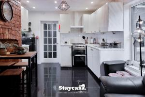 una cocina con armarios blancos y electrodomésticos negros en Astonishing 6 Bedroom 4baths House en Mánchester
