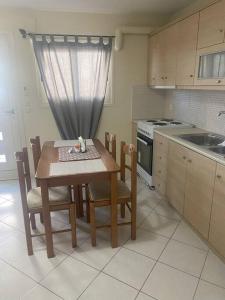 New lovely apartment in Heraklion في مدينة هيراكيلون: مطبخ مع طاولة وكراسي ومغسلة وموقد
