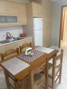 cocina con mesa de madera con sillas y nevera blanca en New lovely apartment in Heraklion en Heraclión