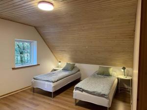 two beds in a room with a wooden ceiling at House in Billund in Billund
