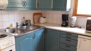a kitchen with blue cabinets and a sink at Mellangårds stugor - Första stugan in Föglö +6 photos