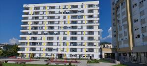 a tall white building with benches in front of it at Apartment Noa in Tuzla