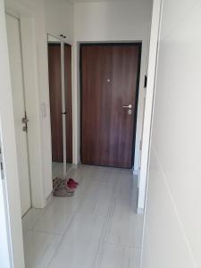 pasillo con puerta de madera y suelo de baldosa blanca en Apartment Noa en Tuzla
