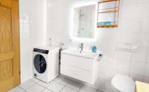 a white bathroom with a washing machine and a sink at Stylish loft with balcony, quiet and spacious in Unterschleißheim