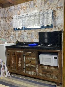 uma cozinha com um lavatório e um micro-ondas em cabana canto da maré em Bombinhas