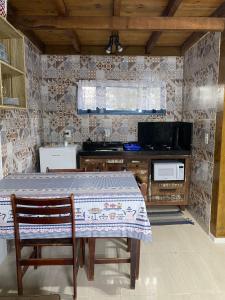 uma cozinha com uma mesa com 2 cadeiras e um fogão em cabana canto da maré em Bombinhas