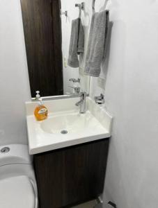 a bathroom with a sink and a toilet and a mirror at Hermoso y Cómodo Apartaestudio 703 in Medellín