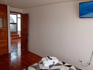 Habitación con TV en la pared y mesa. en Casa Amoblada y Equipada, Completamente Privada en Ibarra