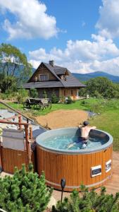 a man in a hot tub in front of a house at Odludomki in Smerek