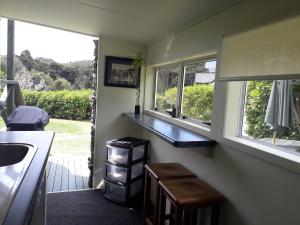 cocina con fregadero, 2 ventanas y barra en Kuaotunu's Peebles Cottage, en Kuaotunu