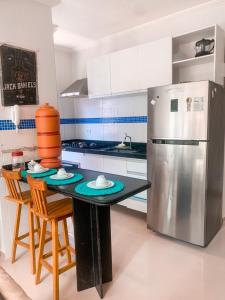 a kitchen with a black table and a refrigerator at CASA EM PORTO DE GALINHAS in Porto De Galinhas