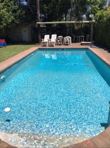 a swimming pool with blue water and two chairs at Mi Bella Vista - Quinta Con Pileta in Bella Vista