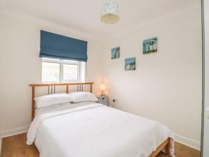 Schlafzimmer mit einem Bett mit weißer Bettwäsche und einem Fenster in der Unterkunft Stunning Seaviews - Beach House - Jacuzzi Bath tub in Littlestone-on-Sea