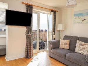 ein Wohnzimmer mit einem Sofa und einem Flachbild-TV in der Unterkunft Stunning Seaviews - Beach House - Jacuzzi Bath tub in Littlestone-on-Sea